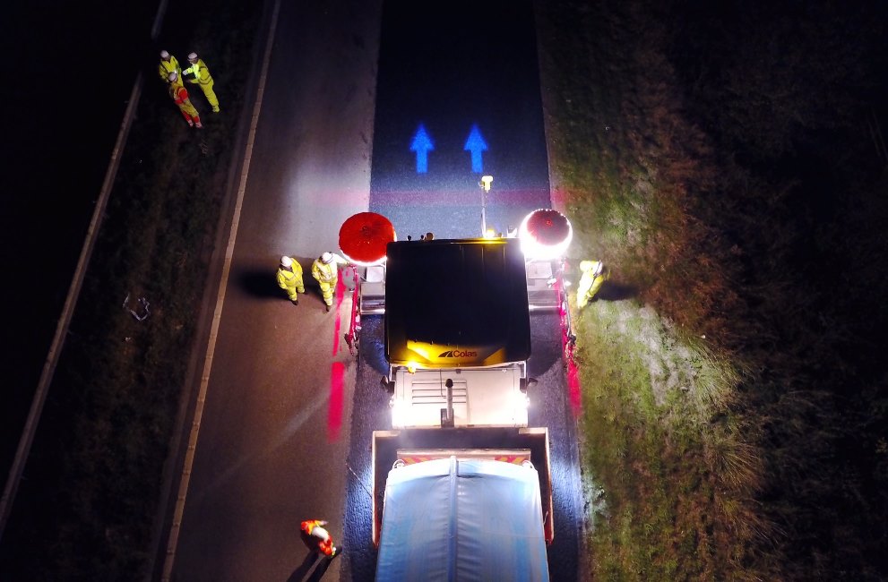 Colas Safety Exclusion Zone marked with red and blue lighting, roadworks at night with plant vehicle and workers.