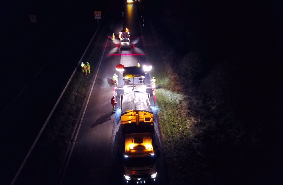 Colas Safety Exclusion Zone marked with red and blue lighting, roadworks at night with plant vehicle and workers.